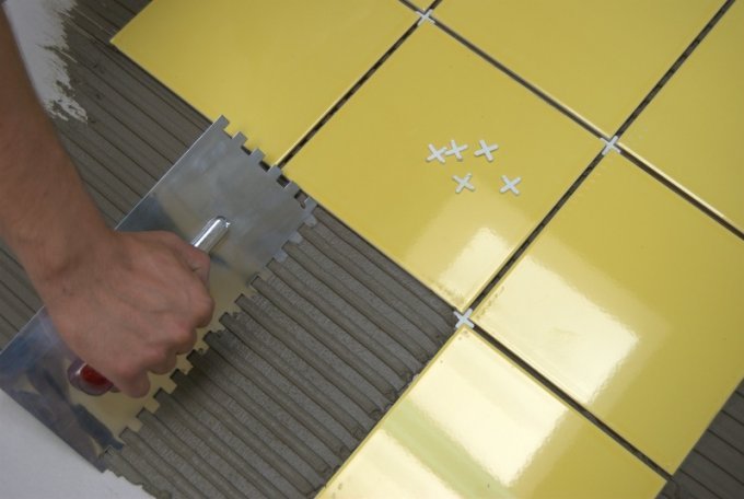 lepljenje rumenih keramičnih ploščic na izravnana tla z uporabo distančnikov